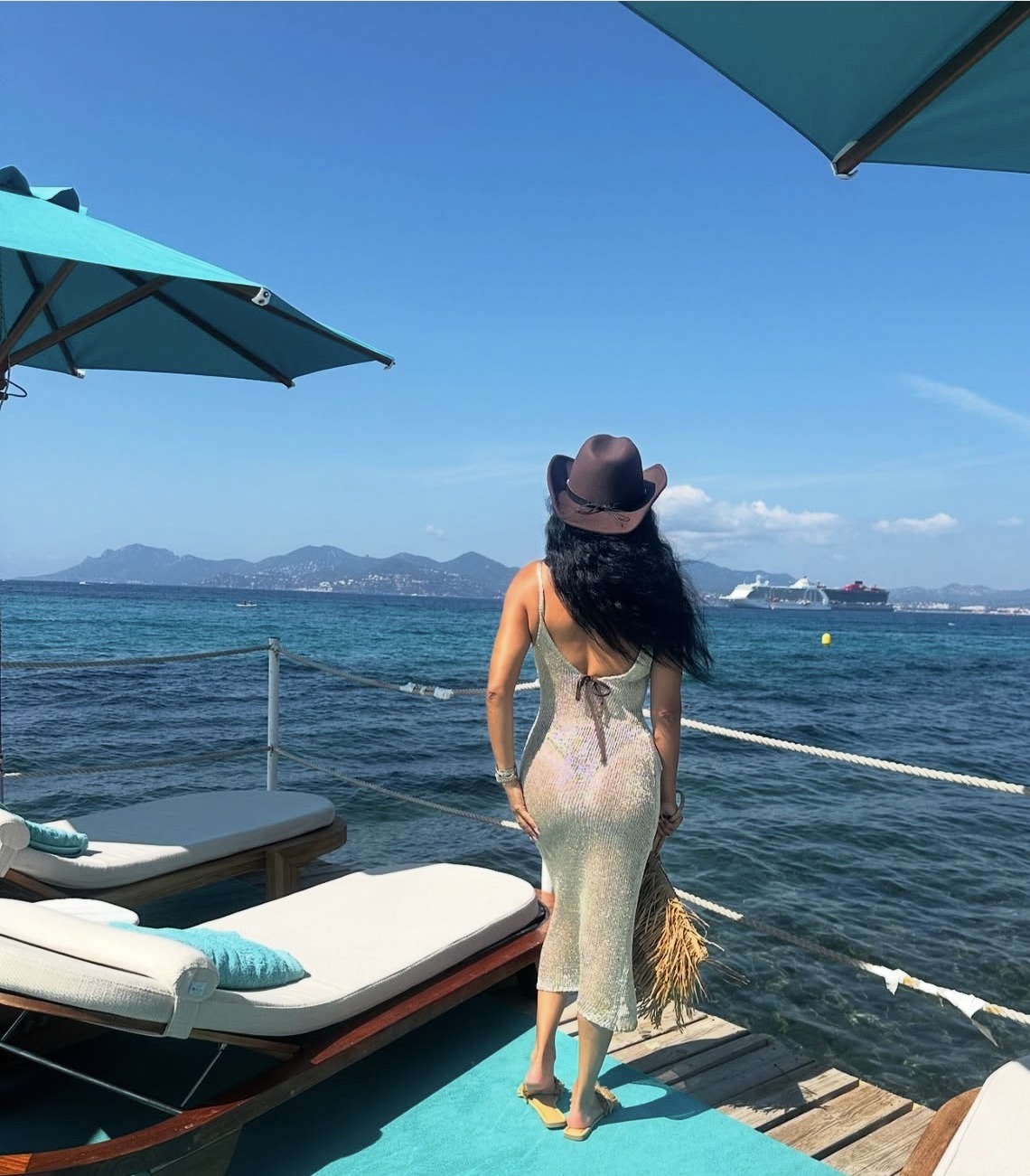 Nakita in a gold dress and cowboy hat overlooking the sea in Cannes, France