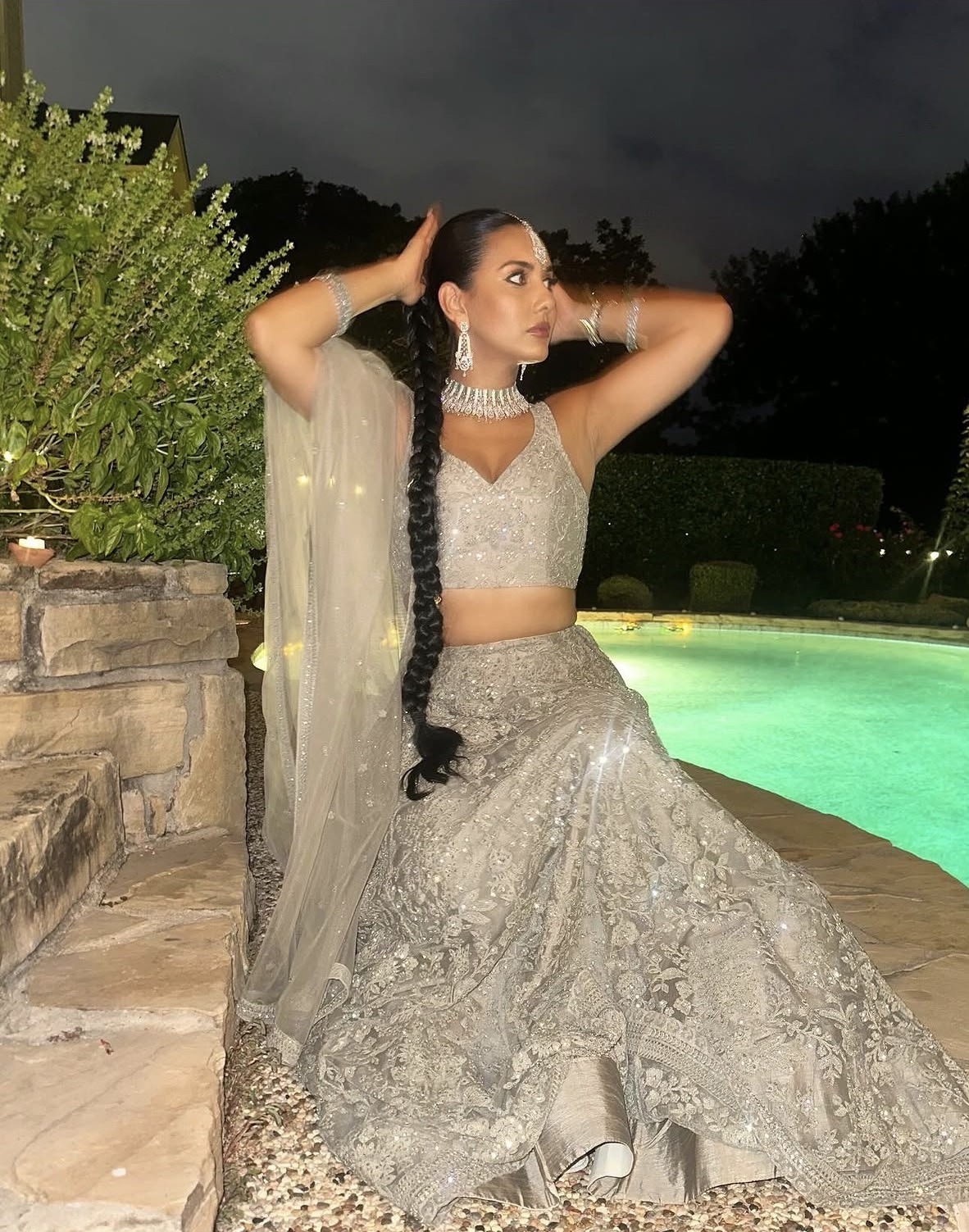 Nakita in a silver embellished lehenga beside a lit pool in Dallas, Texas